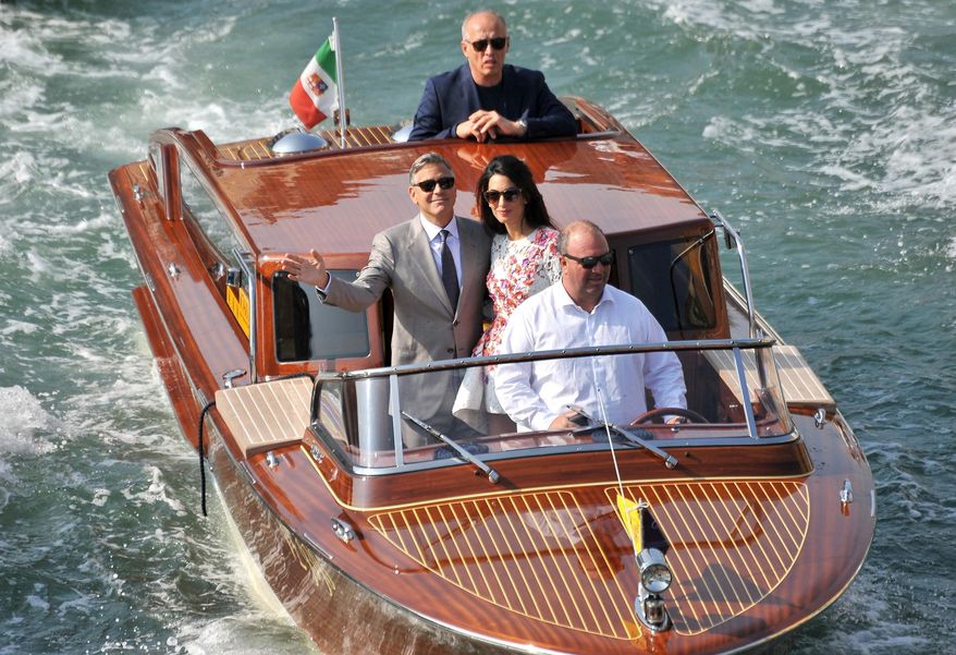 FILE - In this Sept. 28 2014 file photo, George Clooney and his wife Amal Alamuddin, cruise the Grand Canal after leaving the Aman luxury Hotel in Venice, Italy, Sunday, Sept. 28, 2014. This year's Venice Film Festival will include a crime comedy by George Clooney, a Guillermo del Toro fantasy and a Darren Aronofsky thriller. Organizers announced a 21-film competition lineup Thursday that includes the Clooney-directed "Suburbicon," the story of a home invasion gone wrong starring Matt Damon and Julianne Moore. (AP Photo/Luigi Costantini)