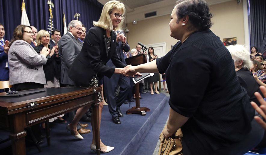 Mass. Sen. Joan Lovely, D-Salem, left, shakes hands with Alejandra Duarte after the Pregnant Workers Fairness Act was signed into law at the Statehouse, Thursday, July 27, 2017, in Boston. Duarte testified before the legislature during April that she was forced to work longer hours with an increased workload after disclosing to her former employer that she was pregnant and wanted a lighter workload, while working at a Worcester laundry. (AP Photo/Charles Krupa)