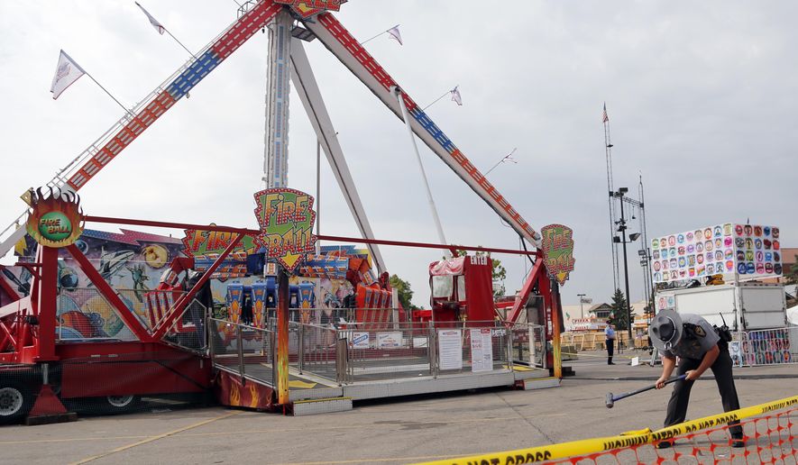 An Ohio State Highway Patrol trooper removes a ground spike from in front of the fire ball ride at the Ohio State Fair Thursday, July 27, 2017, in Columbus, Ohio. The fair opened Thursday but its amusement rides remained closed one day after Tyler Jarrell, 18, was killed and seven other people were injured when the thrill ride broke apart and flung people into the air. (AP Photo/Jay LaPrete)