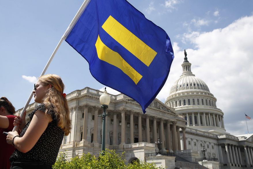 A supporter of LGBT rights holds up an "equality flag" on Capitol Hill in Washington, Wednesday, July 26, 2017, during an event held by Rep. Joe Kennedy, D-Mass. in support of transgender members of the, in response to President Donald Trump's declaration that he wants transgender people barred from serving in the U.S. military "in any capacity," citing "tremendous medical costs and disruption." (AP Photo/Jacquelyn Martin)