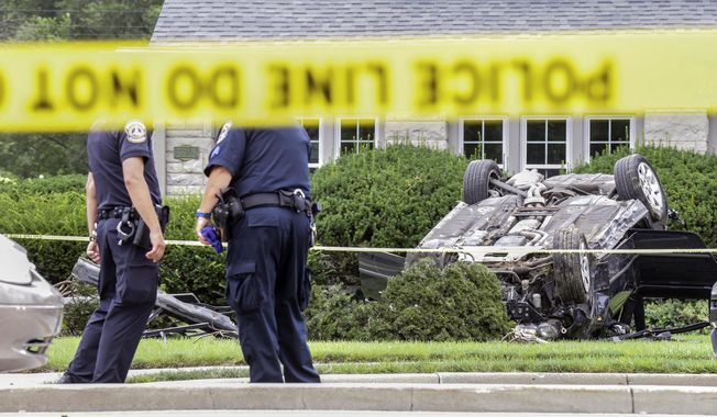 Police examine the scene of a car crash and shooting, Thursday, July 27, 2017 in Indianapolis. A police officer died after being shot multiple times while responding to a traffic crash on the south side of Indianapolis, authorities said Thursday. (Michelle Pemberton/The Indianapolis Star via AP)