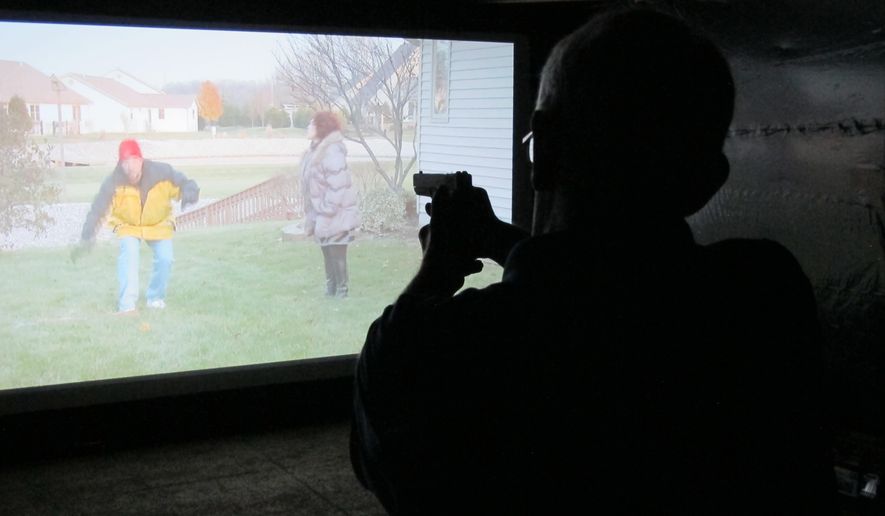 Mark Tulloch, of Kettering, Ohio, takes aim in a firearms training simulator at the Clark County Fair on Wednesday, July 26, 2017, in Springfield, Ohio. The county sheriff rented the simulator to offer as a free exhibit, hoping it will help the public better understand how quickly officers must decide whether to use lethal force. (AP Photo/Kantele Franko)