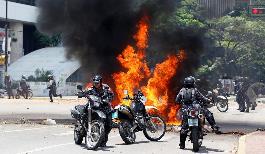 Venezuelan Bolivarian National police move away from the flames after an explosion at Altamira square during clashes against anti-government demonstrators in Caracas, Venezuela, Sunday, July 30, 2017. The explosion injured several officers and damaged several of their motorcycles. The officers were then seen throwing several privately owned motorcycles into the remaining fire in reprisal. (AP Photo/Ariana Cubillos)