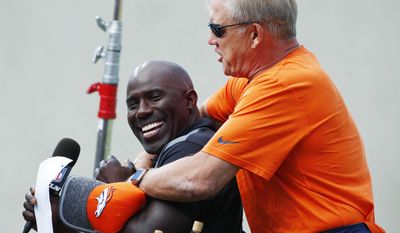 Denver Broncos general manager John Elway, right, hugs former teammate and NFL Hall of Fame inductee for 2017, Terrell Davis, as he waits to interview Elway for a television spot during drills at an NFL football training camp Sunday, July 30, 2017, in Englewood, Colo. (AP Photo/David Zalubowski)