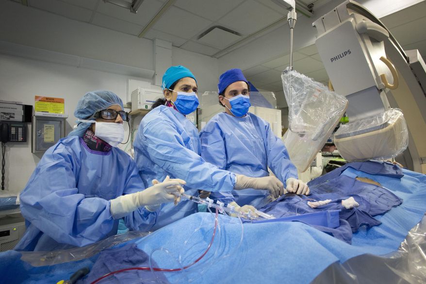 In this Feb. 16, 2017 photo, Dr. Annapoorna Kini, center, performs a non-emergency angioplasty at Mount Sinai Hospital in New York. Through a blood vessel in the groin, she guides a tube to a blockage in the heart. She inflates a tiny balloon to flatten the clog, and leaves behind a mesh tube called a stent to prop the artery open. (AP Photo/Mark Lennihan)