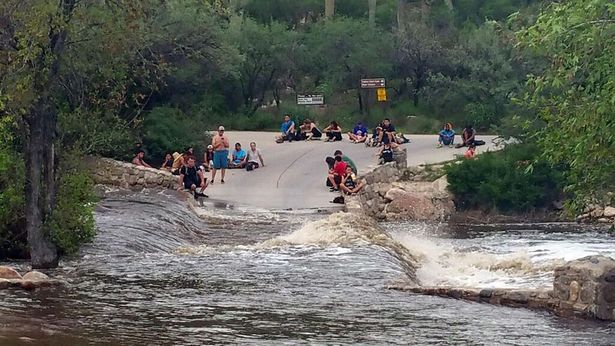 This photo provided by the Pima County Sheriff's office shows hikers stranded by flash flooding in the Sabino Canyon Recreation Park in the outskirts of Tucson, Ariz., Sunday, July 30, 2017. A police helicopter rescued approximately 35 hikers stranded by the flooding a week after 17 people rescued after flash flooding through a different canyon several miles away and 15 days after 10 people died in flash flooding elsewhere in Arizona. (Pima County Sheriff's Office via AP)