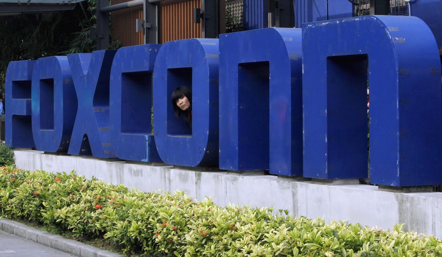 In this May 27, 2010, file photo, a worker looks out through the logo at the entrance of the Foxconn complex in the southern Chinese city of Shenzhen. Conservationists are lining up to oppose Republican plans to eliminate key environmental regulations as part of an incentive package to lure a $10 billion Foxconn electronics plant to southeastern Wisconsin. Gov. Scott Walker&#39;s incentives bill would exempt the company from environmental impact statements and state permits for filling wetlands and building on lake beds. (AP Photo/Kin Cheung, File)