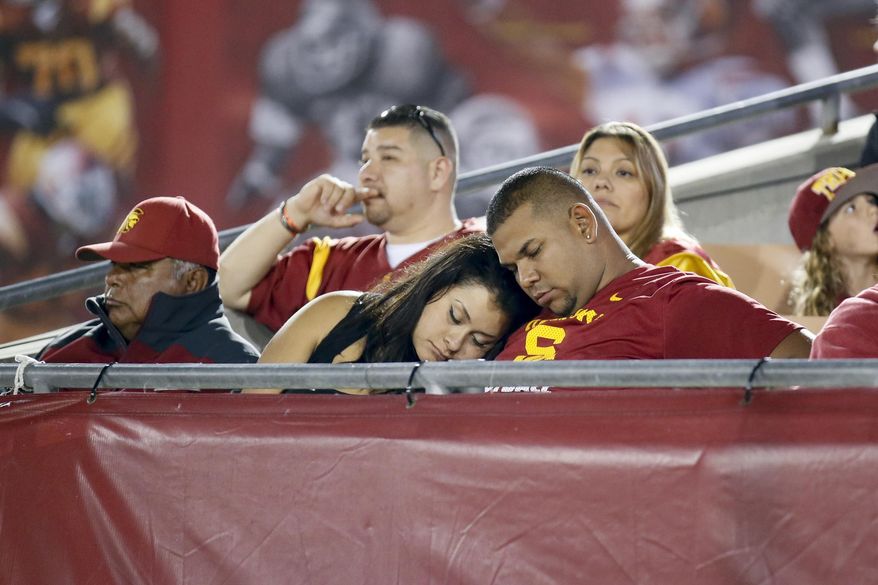 FILE - In this Sept. 5, 2015, file photo, Southern California fans sleep at the end of an NCAA college football game against Arkansas State, in Los Angeles. To keep fans in the stands and those watching on TV or mobile devices engaged, the NFL, NBA and Major League Baseball have taken steps to shorten games. Now it’s college football’s turn. (AP Photo/Danny Moloshok, File)