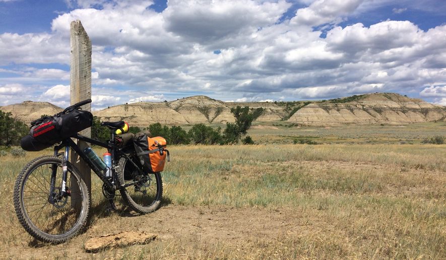 This June 19, 2017 photo shows a fully loaded hardtail mountain bike propped up by a trail-marking post on the Maah Daah Hey Trail near Medora, North Dakota. The wooden fence posts placed along the trail were within sight of each other for easy navigation. (AP Photo/Carey J. Williams)