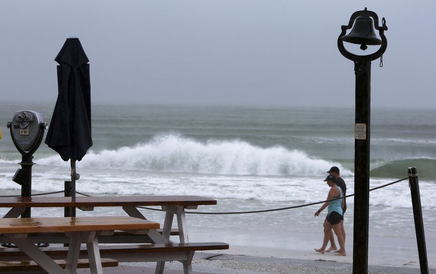 Waves kick up as people walk on Pass-a Grille Beach, St. Pete Beach, Fla., Monday, July 31, 2017. Tropical Storm Emily began trekking east across the Florida peninsula on Monday, scattering drenching rains amid expectations it would begin weakening in the coming hours on its approach to the Atlantic coast. (Scott Keeler/Tampa Bay Times via AP)