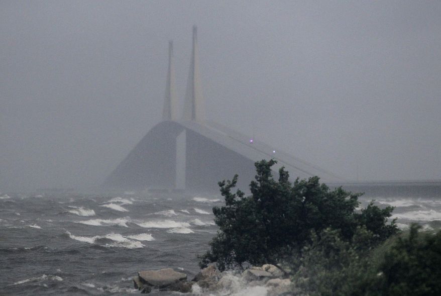 Waves hit the shore as Sunshine Skyway Bridge, which is was closed due to high winds, is seen in the background Monday, July 31, 2017, in St. Petersburg, Fla. Tropical Storm Emily began trekking east across the Florida peninsula on Monday, scattering drenching rains amid expectations it would begin weakening in the coming hours on its approach to the Atlantic coast. (Dirk Shadd/Tampa Bay Times via AP)