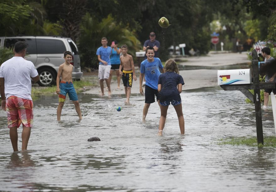 Members of the Leonard and Wilkins families from North Carolina play floodwater in Fort Myers Beach, Fla., Monday, July 31, 2017. Tropical Storm Emily began trekking east across the Florida peninsula on Monday, scattering drenching rains amid expectations it would begin weakening in the coming hours on its approach to the Atlantic coast. (Andrew West/The News-Press via AP)