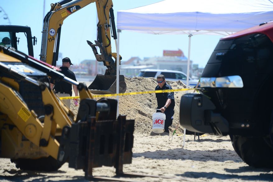 In this Monday, July 31, 2017, photo, Ocean City Police carry out buckets of sand to be sifted from a deep hole that was dug around the area where a body was found in Ocean City, Md. Police say the body of Ashley O'Connor, a 30-year-old Texas woman, was found buried on the beach with just an arm above the sand. (Megan Raymond/The Daily Times via AP)