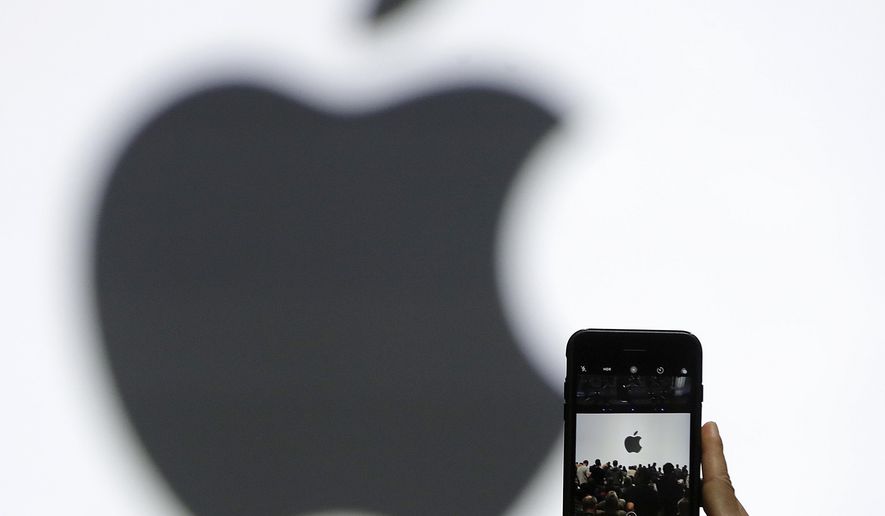 In this Monday, June 5, 2017, file photo, a person takes a photo of an Apple logo before an announcement of new products at the Apple Worldwide Developers Conference in San Jose, Calif. Apple is getting ready to use iPhone cameras as an entryway into the strange world of augmented reality, taking the trend-setting company down an avenue that could usher in a new era in technology. (AP Photo/Marcio Jose Sanchez, File)