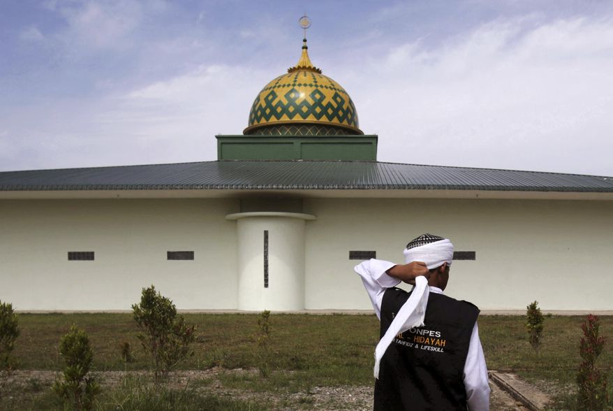 In this July 22, 2017, photo, a student adjusts his turban outside the mosque at Al Hidayah Islamic Boarding School in Sei Mencirim, North Sumatra, Indonesia. Pupils at the boarding school are the sons of Islamic militants whose fathers were killed in police raids or are in prison for terrorism offenses. Former radical preacher Khairul Ghazali set founded the school to prevent the boys, who were ostracized and taunted at mainstream schools, from becoming the next generation of Indonesian jihadists. (AP Photo/Binsar Bakkara)