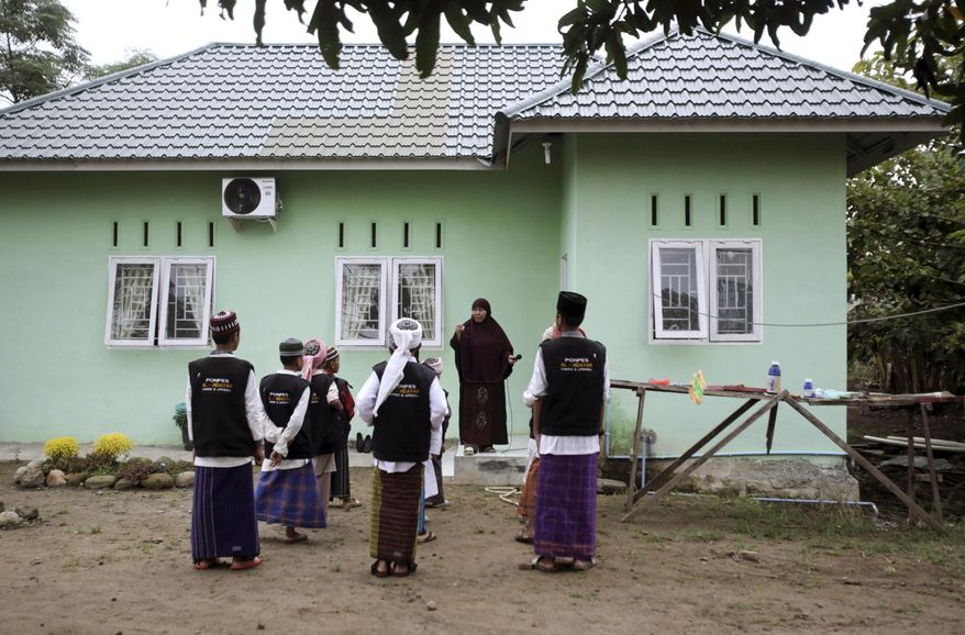 In this July 22, 2017, photo, Kartini Panggabean, center, talks to students at Al Hidayah Islamic Boarding School in Sei Mencirim, North Sumatra, Indonesia. Kartini and her husband former radical preacher Khairul Ghazali set up the school for the sons of Islamic militants whose fathers are either killed in raids or in prison for terrorism offenses aimed at preventing them from becoming the next generation of Indonesian jihadists. (AP Photo/Binsar Bakkara)