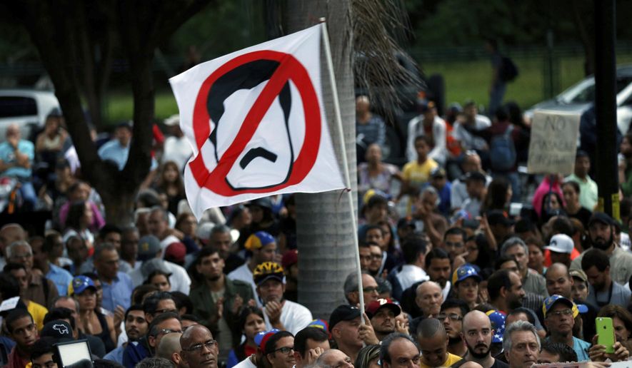 An anti-government demonstrator waves a flag against Venezuela&#39;s President Nicolas Maduro during a vigil in honor of those who have been killed during clashes between security forces and demonstrators in Caracas, Venezuela, Monday, July 31, 2017. Many analysts believe Sunday&#39;s vote for a newly elected assembly that will rewrite Venezuela’s constitution will catalyze yet more disturbances in a country that has seen four months of street protests in which at least 125 people have died. (AP Photo/Ariana Cubillos)