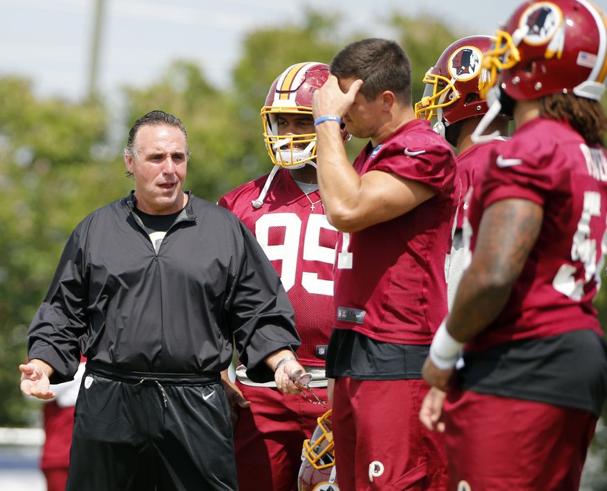 Washington Redskin defensive line coach, Jim Tomsula, left, talks with his players during practice at the Washington Redskins NFL training camp in Richmond, Va., Wednesday, Aug. 2, 2017. (AP Photo/Steve Helber)