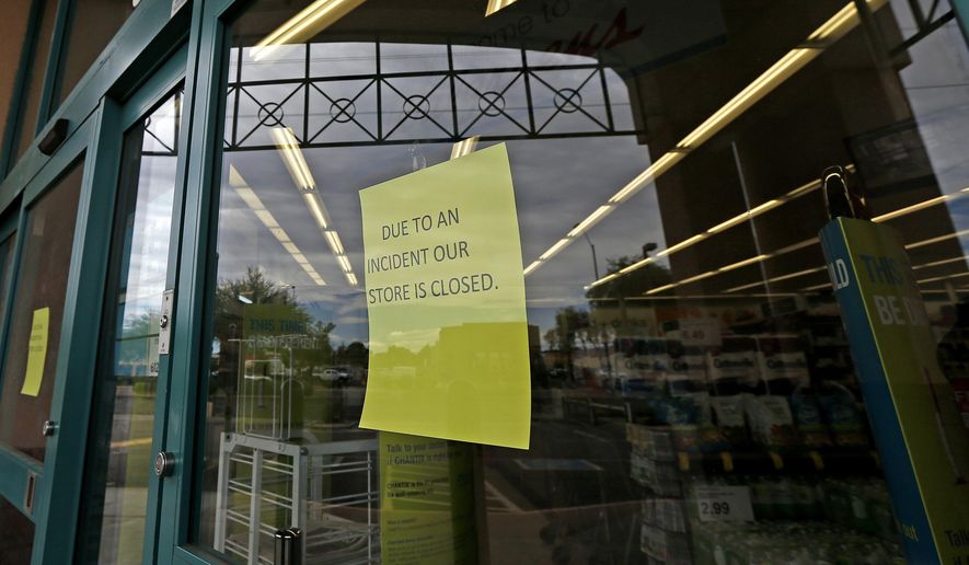 Signs posted at the entrance of a local Walgreens let possible customers know that the store remains closed Wednesday, Aug. 2, 2017, in Phoenix, after a customer at the drugstore shot and killed a man who was attempting to rob the pharmacy Tuesday night, according to police. (AP Photo/Ross D. Franklin)