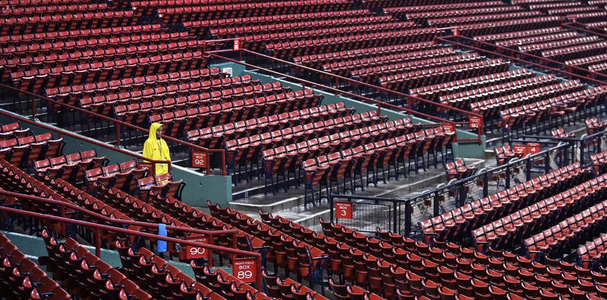 Boston Red Sox usher Kathy Gould, of Boston, stands in the pouring rain while keeping fans away from the seating bowl due to the weather prior to a scheduled baseball game against the Cleveland Indians at Fenway Park, Wednesday, Aug. 2, 2017, in Boston. The game was delayed due to heavy rain and thunderstorms. (AP Photo/Charles Krupa)