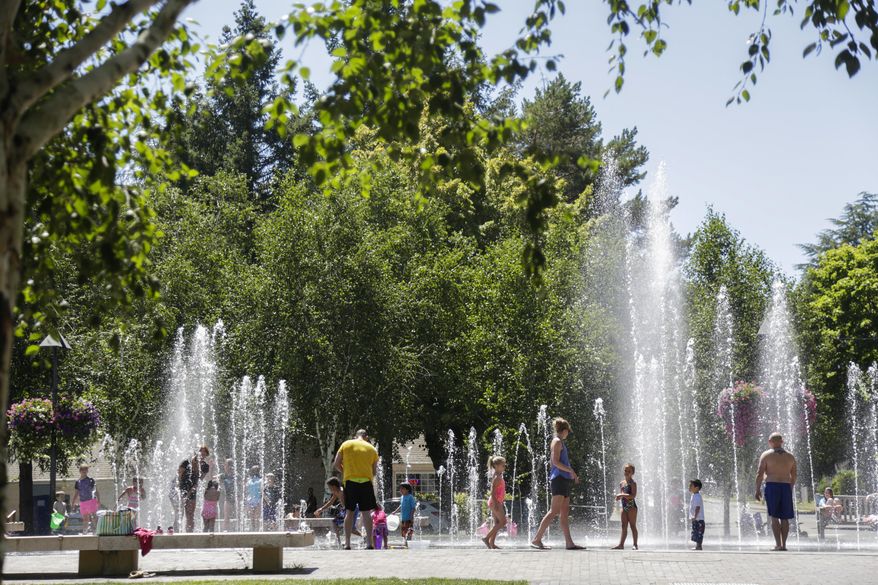 In this Tuesday, Aug. 1, 2017 photo, residents cooled off splashing in the water at Beaverton City Park in Beaverton, Ore. Scorching temperatures are predicted for the Northwest Wednesday and Thursday, with forecasters saying Seattle and Portland could top triple digits and break records. (Stephanie Yao Long/The Oregonian via AP)