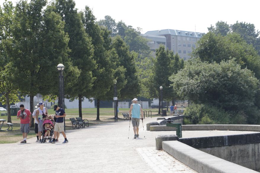 Dave Thysell, right, walks around Capitol Lake in Olympia, Wash., on Wednesday, Aug. 2, 2017, as temperatures were expected to climb to near 100 degrees. Scorching temperatures are predicted for the Pacific Northwest Wednesday and Thursday, with forecasters saying some cities in the region could top triple digits and break records. (AP Photo/Rachel La Corte)