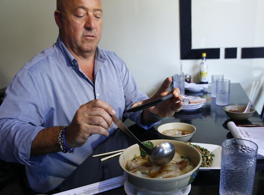 In this Thursday, July 20, 2017 photo, Travel Channel's "Bizzare Foods" host Andrew Zimmern, a four-time James Beard award-winning chef, takes a cell phone photo of his Taiwanese noodle soup at Happy Stony Noodle in Elmhurst, Queens in New York. The chef's new show, "The Zimmern List," debuts early 2018. It showcases Zimmern's favorite places, "where I actually go when the cameras aren't rolling." (AP Photo/Kathy Willens)