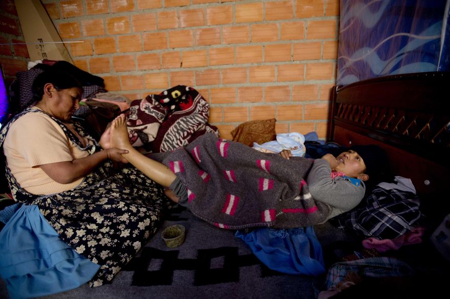 In this June 20, 2017 photo, midwife Ana Choque massages the feet of Mariana Limachi two weeks after delivering Limachi's first child at her home in El Alto, Bolivia. Maternal deaths in Bolivia are concentrated among poor, rural indigenous women. Critics say Bolivia's public health centers and hospitals in rural areas often lack beds, doctors and medicines. "An equally important factor is the fact that indigenous women who have managed to get to clinics have often been treated as second-class citizens, scorned because of their gender, their ethnicity and their traditions," the U.N. body said in a 2009 report. (AP Photo/Juan Karita)