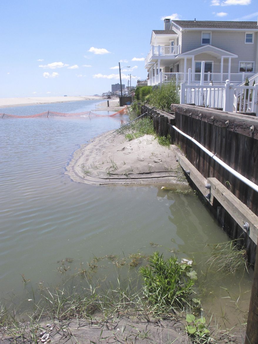 This July 31, 2017 photo shows floodwaters on the beach up against an oceanfront house in Margate N.J. days after heavy rains created large ponds of standing water on the beach. On Thursday Aug. 3, 2017, a judge ordered the immediate shutdown of the sand dune construction project that caused the water to collect on the beach, and gave the federal, state and local governments a week to come up with an engineering solution. (AP Photo/Wayne Parry)