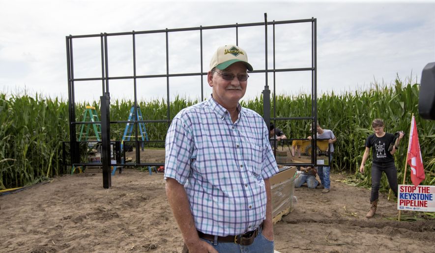 In this July 29, 2017, photo, corn farmer Jim Carlson of Silver Creek, Nebraska, waits to be interviewed by a television reporter while standing in front of solar panels he is building on his land in the proposed path of the Keystone XL pipeline. Despite new uncertainty over whether TransCanada, the builder of the Keystone XL pipeline will continue the project, longtime opponents in Nebraska aren't letting their guard down and neither are law enforcement officials who may have to react to protests if it wins approval. (AP Photo/Nati Harnik)