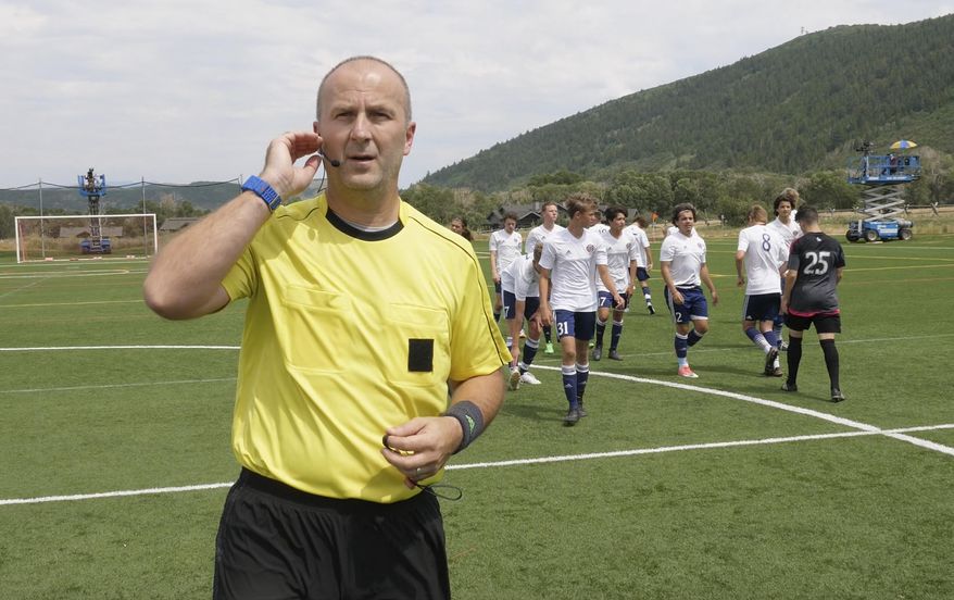 In this July 11, 2017, still image from video, MLS referee Silviu Petrescu tests an earpiece and mic used to communicate with a video assistant referee during a video replay scrimmage organized in a community park, in Park City, Utah. Games were staged as part of the final training camp to gauge MLS referees' competence in and comfort with video replay. (AP Photo/Rick Bowmer)