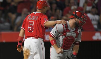 Los Angeles Angels' Albert Pujols, left, puts his hand on the shoulder of Philadelphia Phillies catcher Cameron Rupp after scoring on a single by Andrelton Simmons during the third inning of a baseball game, Wednesday, Aug. 2, 2017, in Anaheim, Calif. (AP Photo/Mark J. Terrill)