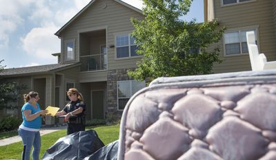 ADVANCE FOR USE SATURDAY, AUG 5 - In this Thursday, July 27, 2017 photo, Larimer County, Colo., Sheriff&#39;s Department deputy Barb Bowman hands paperwork to a homeowner after a tenant was evicted from a condominium in south Fort Collins, Colo. (Austin Humphreys/The Coloradoan via AP)