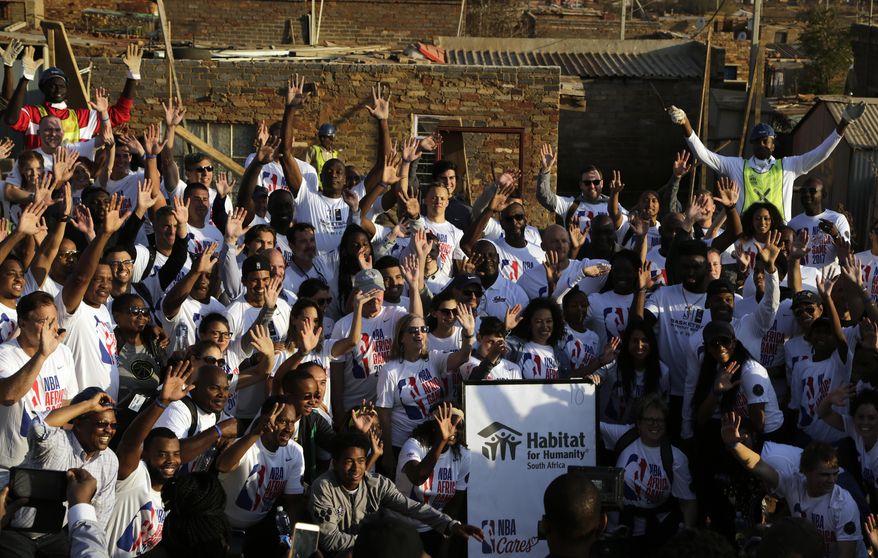NBA staff, players and their families members, pose for a group photograph after helping out in building houses in Lenasia South of Johannesburg, South Africa, Thursday, Aug. 3, 2017. As part of the NBA Africa Game, and Habitat for Humanity South Africa, 200 volunteers from the NBA players, families and executives help build 10 homes. (AP Photo/Themba Hadebe)