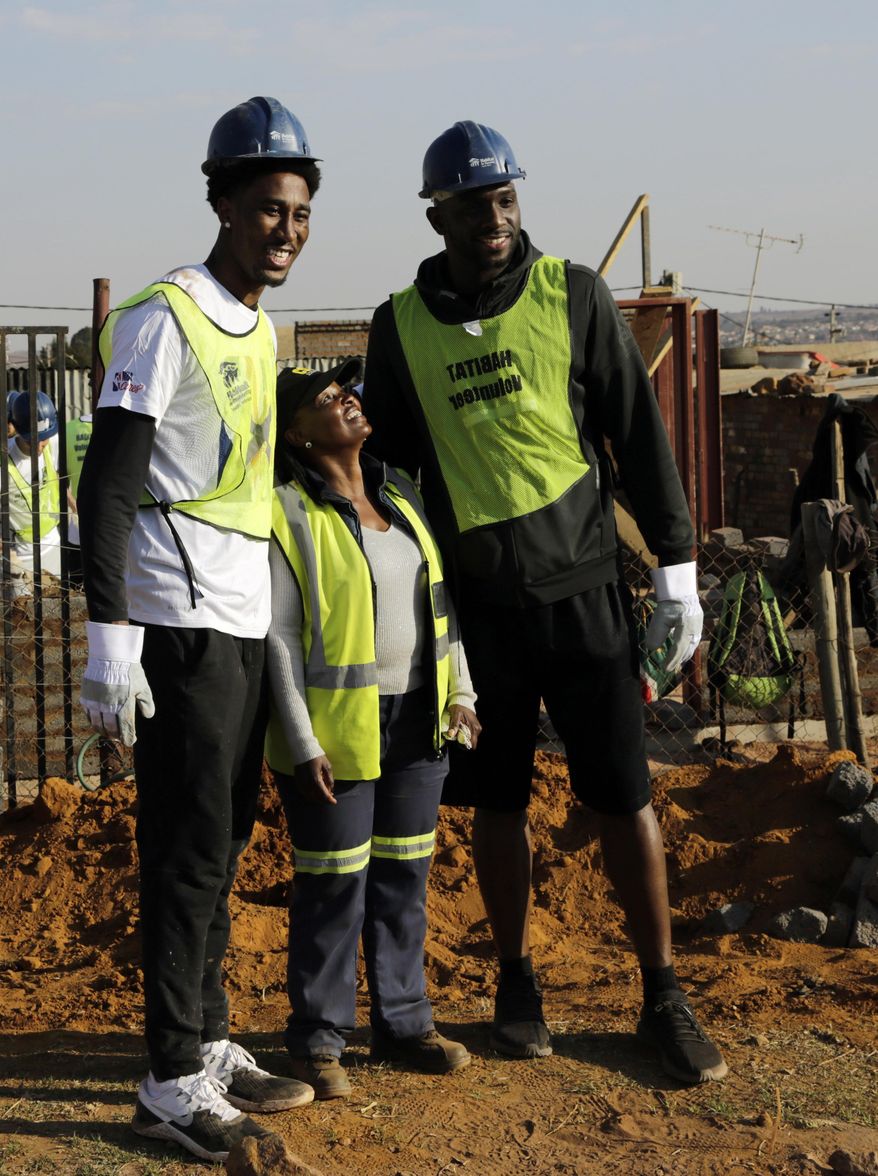 Rondae Hollis-Jefferson of Brooklyn Nets, left, and Kemba Walker of Charlotte Hornets pose for a photograph with a local volunteer whilst helping in building a house in Lenasia, south of Johannesburg, South Africa, Thursday, Aug. 3, 2017. As part of the NBA Africa Game, and Habitat for Humanity South Africa, 200 volunteers from the NBA players, families and executives help build 10 homes. (AP Photo/Themba Hadebe)