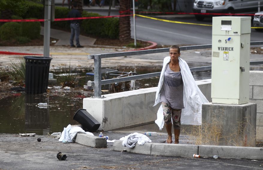 A woman walks near The Linq Hotel where several people were rescued from flooding after thunderstorms passed through in Las Vegas on Friday, Aug. 4, 2017. (Chase Stevens/Las Vegas Review-Journal via AP)