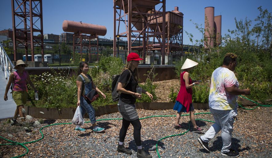 In this Aug. 1, 2017, photo, volunteers and crew arrive on the Swale in New York. The Swale garden is an old construction barge planted with vegetables, apple trees and fragrant herbs that gives New Yorkers a chance to pick their own dinners. (AP Photo/Michael Noble Jr.)