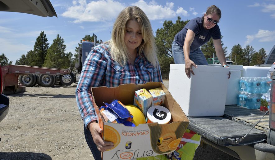 Alaina Browning, left, and Amanda Anderson load Browning's pickup struck with donated food and water to help those still working on the Lodgepole Complex Fire burning in Garfield and Petroleum Counties. As of Thursday the fire was 62 percent contained after burning 270,200 acres. (Rion Sanders/Great Falls Tribune via AP)