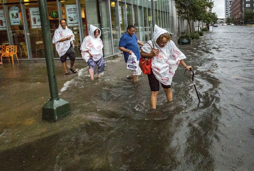 CORRECTS CREDIT TO THE ADVOCATE - In this Saturday, Aug. 5, 2017, photo, Philana Crite, of Cleveland who was in town for a family reunion, steps of the curb into flood waters in the New Orleans. Parts of New Orleans flooded after a heavy weekend rainfall that officials said overwhelmed the city's pump stations. (Scott Threlkeld/The Advocate via AP)