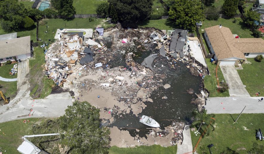 FILE - This Friday, Aug. 4, 2017 file photo shows a large sinkhole in the Lake Padgett Estates community in Land O' Lakes, Fla. Florida officials have condemned two more homes due to a Florida sinkhole, bringing the total to six homes that are now unlivable. Authorities said in a news release Sunday that the two additional homes were being condemned. Two homes were condemned Saturday and two were destroyed when the ground caved in on July 14. (Luis Santana Tampa Bay Times via AP, File)