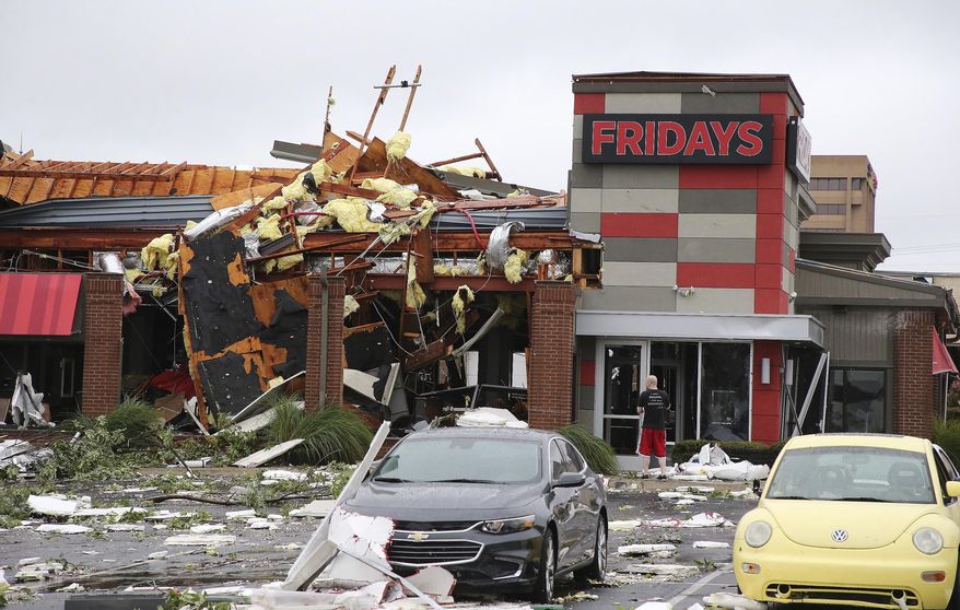 A man stands outside a Fridays restaurant after a storm moved through the area in Tulsa, Okla., Sunday, Aug. 6, 2017. A possible tornado struck near midtown Tulsa and causing power outages and roof damage to businesses. (Tom Gilbert/Tulsa World via AP)