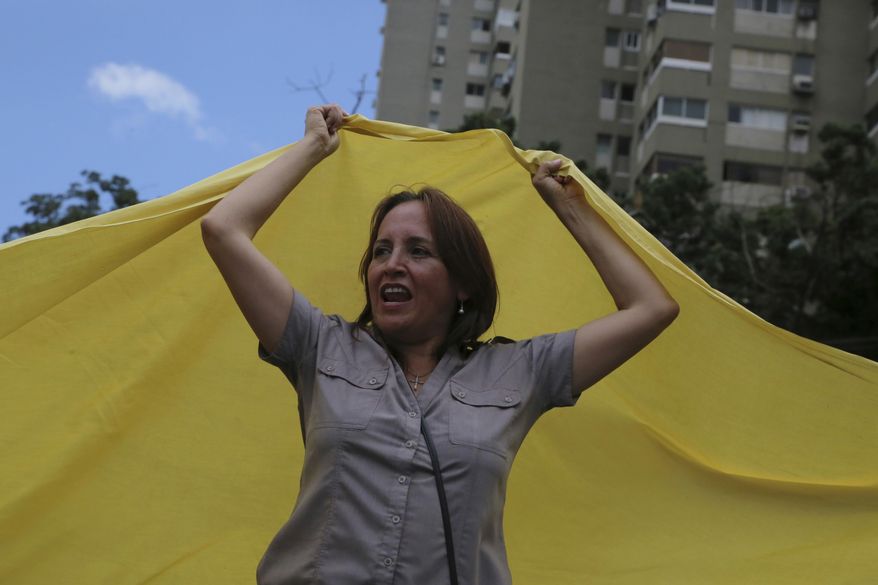 An anti-government demonstrator waves a large Venezuelan flag during a protest against the government of Venezuela's President Nicolas Maduro in Caracas, Venezuela, Sunday, Aug. 6, 2017. Months of protests are fueled by widespread anger over food shortages, triple-digit inflation and high crime. (AP Photo/Wil Riera)
