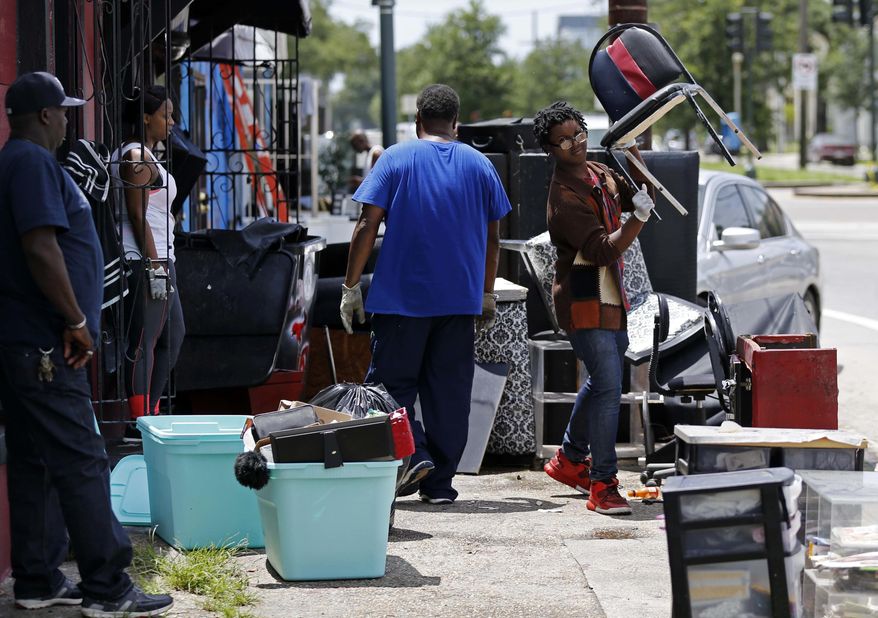 Jomel Walker, right, helps his parents throw out soggy furniture from their Crown And Glory Beauty Salon, in the aftermath of the past weekend's torrential rains, in New Orleans, Monday, Aug. 7, 2017. (AP Photo/Gerald Herbert)