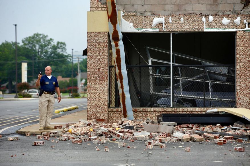 A Tulsa Police Officer uses his cell phone to record tornado damage at Highland Plaza in Tulsa, Okla., Monday, Aug. 7, 2017. (Mike Simons/Tulsa World via AP)