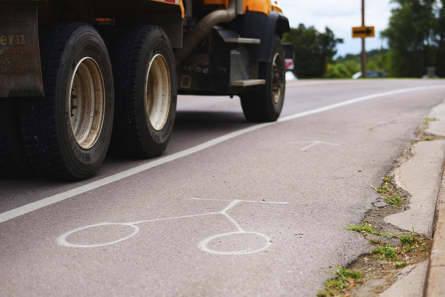 In this Aug. 3, 2017 photo, a vehicle makes its way on North drive in front of South Dakota State Penitentiary in Sioux Falls, S.D. High speeds and heavy traffic on the road leading to the state's largest prison have Sioux Falls and the state Department of Corrections looking at ways to improve safety. The city painted a bike lane and narrowed driving lanes along North Drive this spring and will use traffic counters to judge if speeds drop enough to create safer conditions. (Briana Sanchez/The Argus Leader via AP)