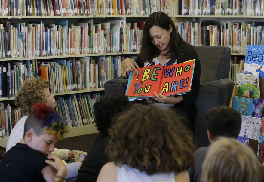 In this Wednesday, July 12, 2017 photo, Sandra Collins, executive director and founder of enGender, reads a book to campers at the Bay Area Rainbow Day Camp in El Cerrito, Calif. Collins says, “A lot of these kids have been bullied and had trauma at school. This is a world where none of that exists, and they're in the majority. That’s a new experience for kids who are used to hiding and feeling small.” (AP Photo/Jeff Chiu)