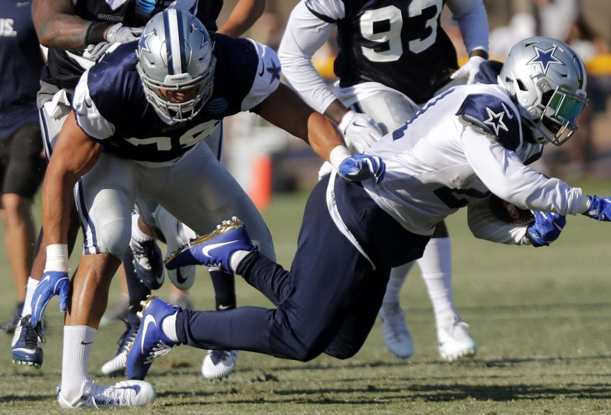 Tyrone Crawford tackles Ezekiel Elliott in football practice as the Dallas Cowboys hold training camp in Oxnard, Calif., Tuesday, Aug. 8, 2017. Crawford badly turned his left ankle making the tackle but there was no immediate word on the severity of the injury. Crawford has started 45 games at end and defensive tackle over the past three seasons since missing all of 2013 after tearing his left Achilles tendon in training camp. (Rodger Mallison/Star-Telegram via AP)