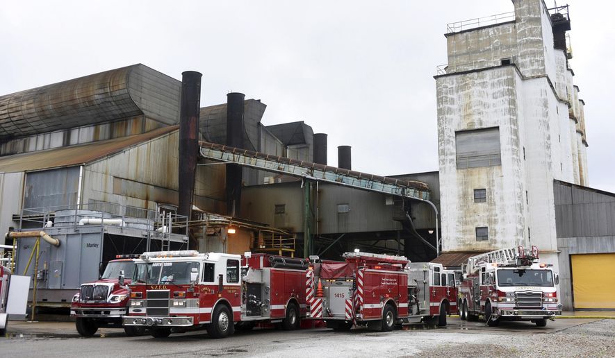 In this Monday, Aug. 7, 2017 photo, fire trucks sit at the Owens-Illinois glass plant in Zanesville, Ohio. Authorities said tons of molten glass spilled from a ruptured tank at the Ohio plant, oozing like lava from a small hole that quickly grew several feet wide. (Chris Crook/Times Recorder via AP)