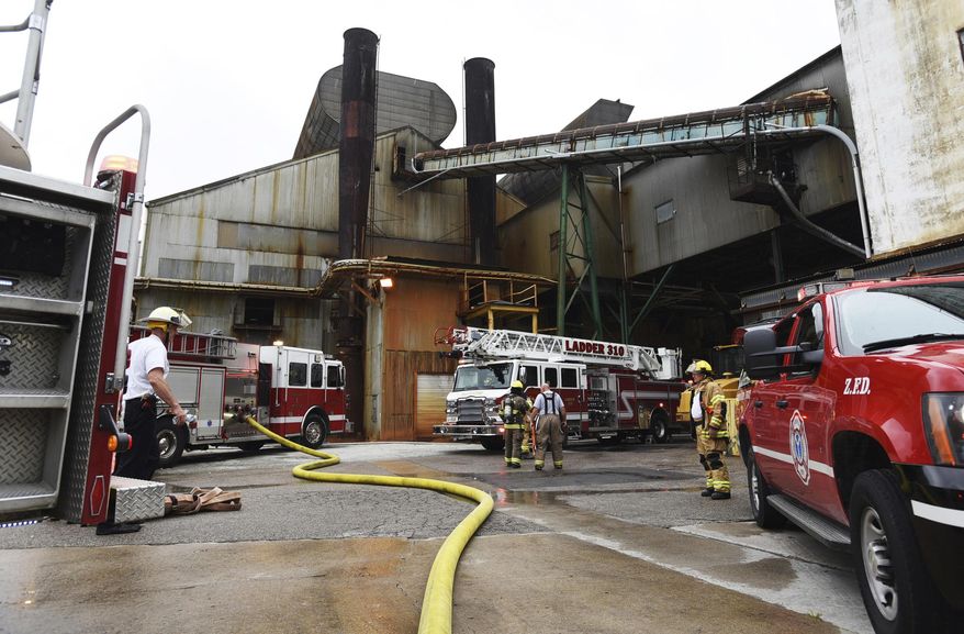 In this Monday, Aug. 7, 2017 photo, emergency personnel work at the Owens-Illinois glass plant in Zanesville, Ohio. Authorities said tons of molten glass spilled from a ruptured tank at the Ohio plant, oozing like lava from a small hole that quickly grew several feet wide. (Chris Crook/Times Recorder via AP)