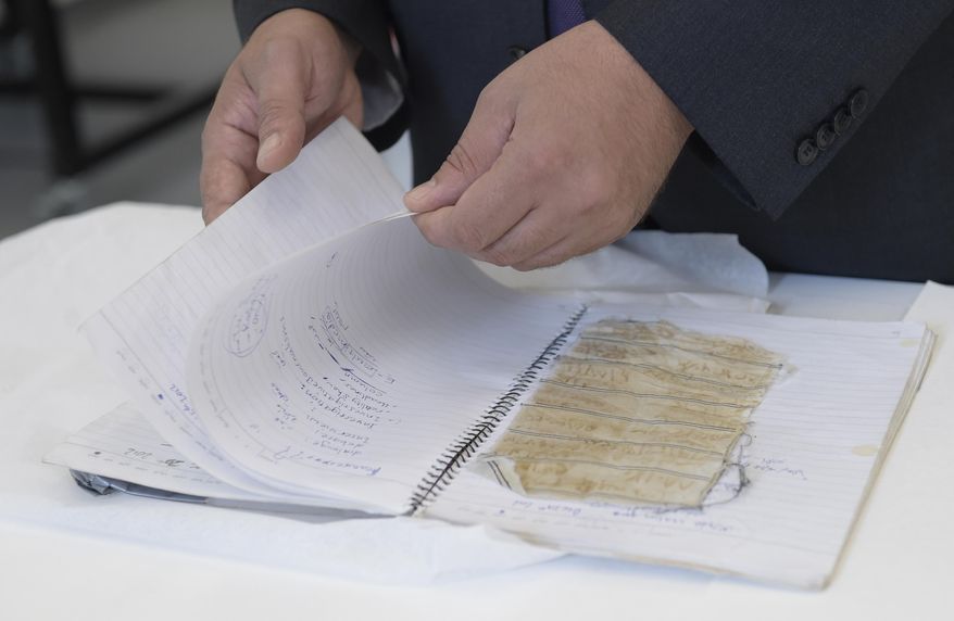 Mansour al-Omari, a Syrian human-rights activist documenting cases of people who have disappeared under President Bashar Assad's government, shows scraps of fabric with the names of fellow inmates he is presenting to the U.S. Holocaust Memorial Museum for preservation at the conservation center, Tuesday, Aug. 8, 2017, in Bowie, Md. (AP Photo/Susan Walsh)